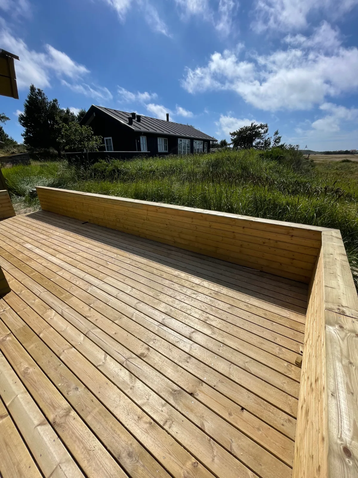 Ny terrasse med vindafskærmning i træ ved sommerhus i klitlandskab