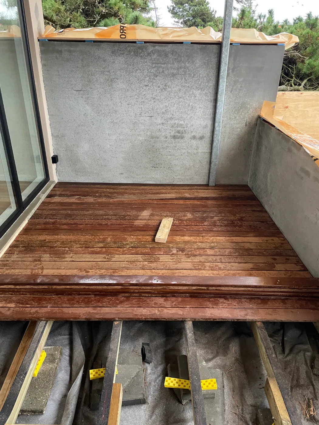 Ny terrasse i mørkt IPE-træ lagt an mod en betonvæg